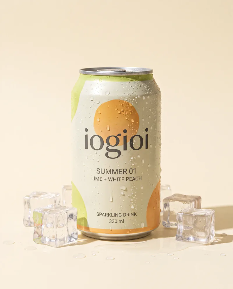 Lata de bebida con gas iogioi Summer 01, de lima y melocotón blanco, 330 ml, cubierta de gotas y rodeada de cubitos de hielo